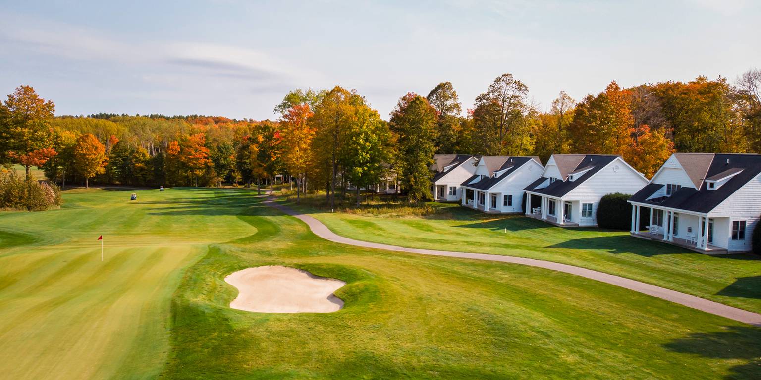 Fairway, sand bunkers of autumn golf course lined by white cottages, Crooked Tree Golf Club