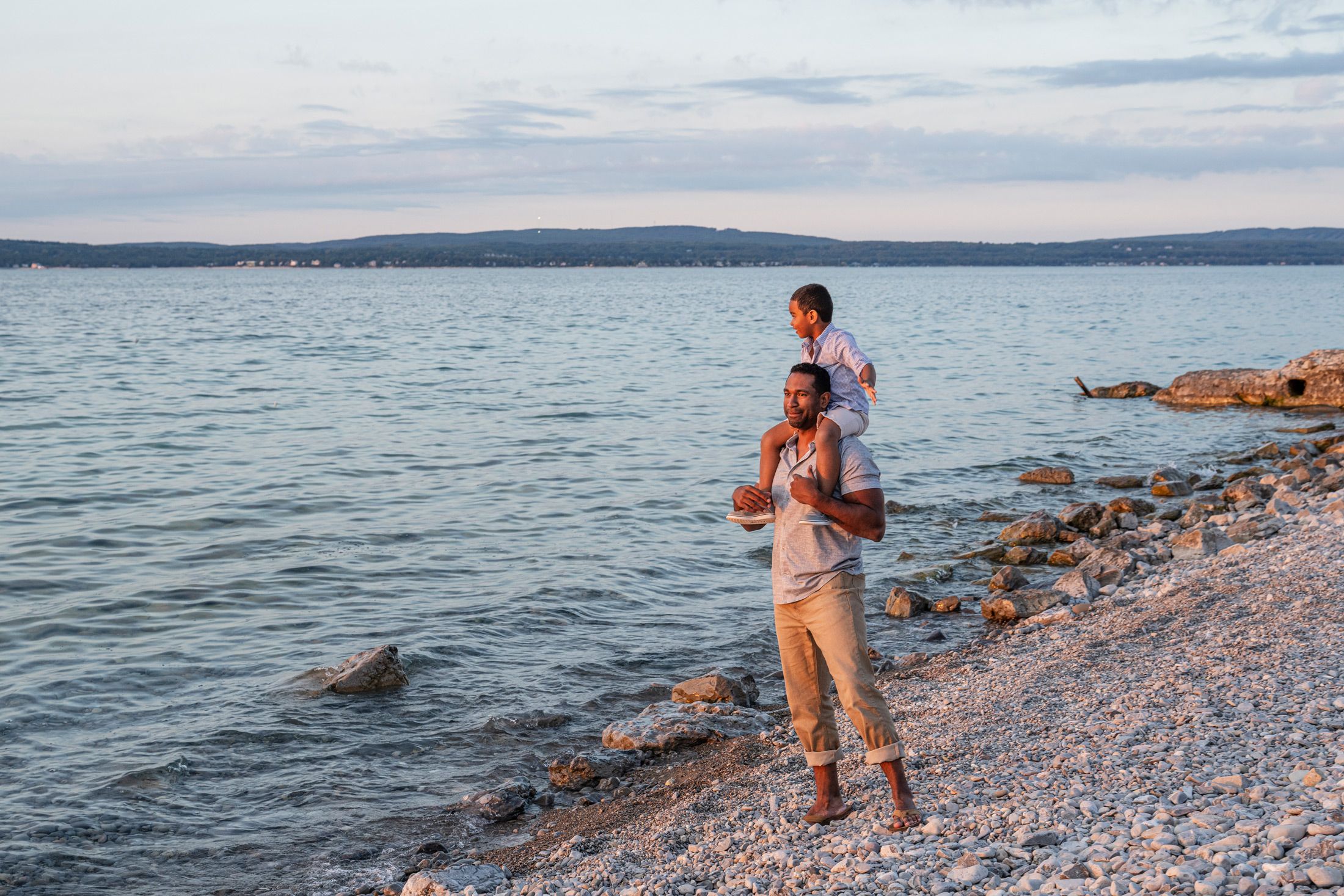 Father and son gazing at water along rocky lake shore, Inn at Bay Harbor