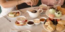 Afternoon Tea table as women steep tea, floral tea cups