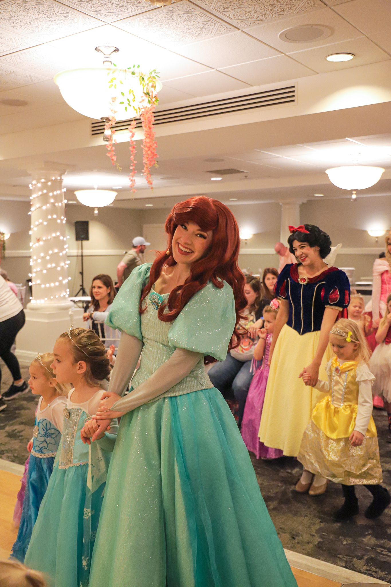 Princess Ariel character smiles while holding hands with guests, Inn at Bay Harbor