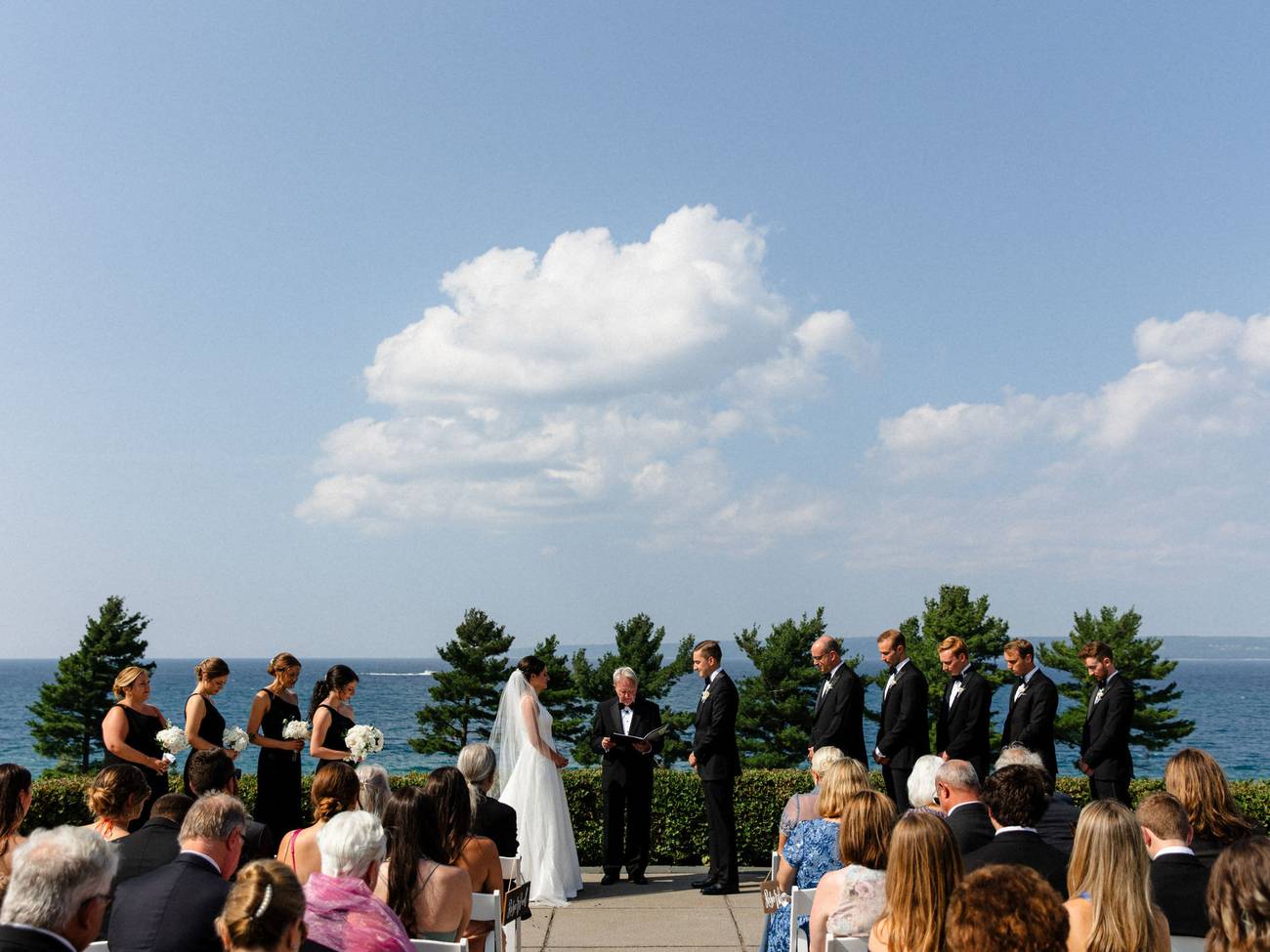 Wedding guests look on as  couple says vows in front of Lake Michigan, Bay Harbor Golf Club