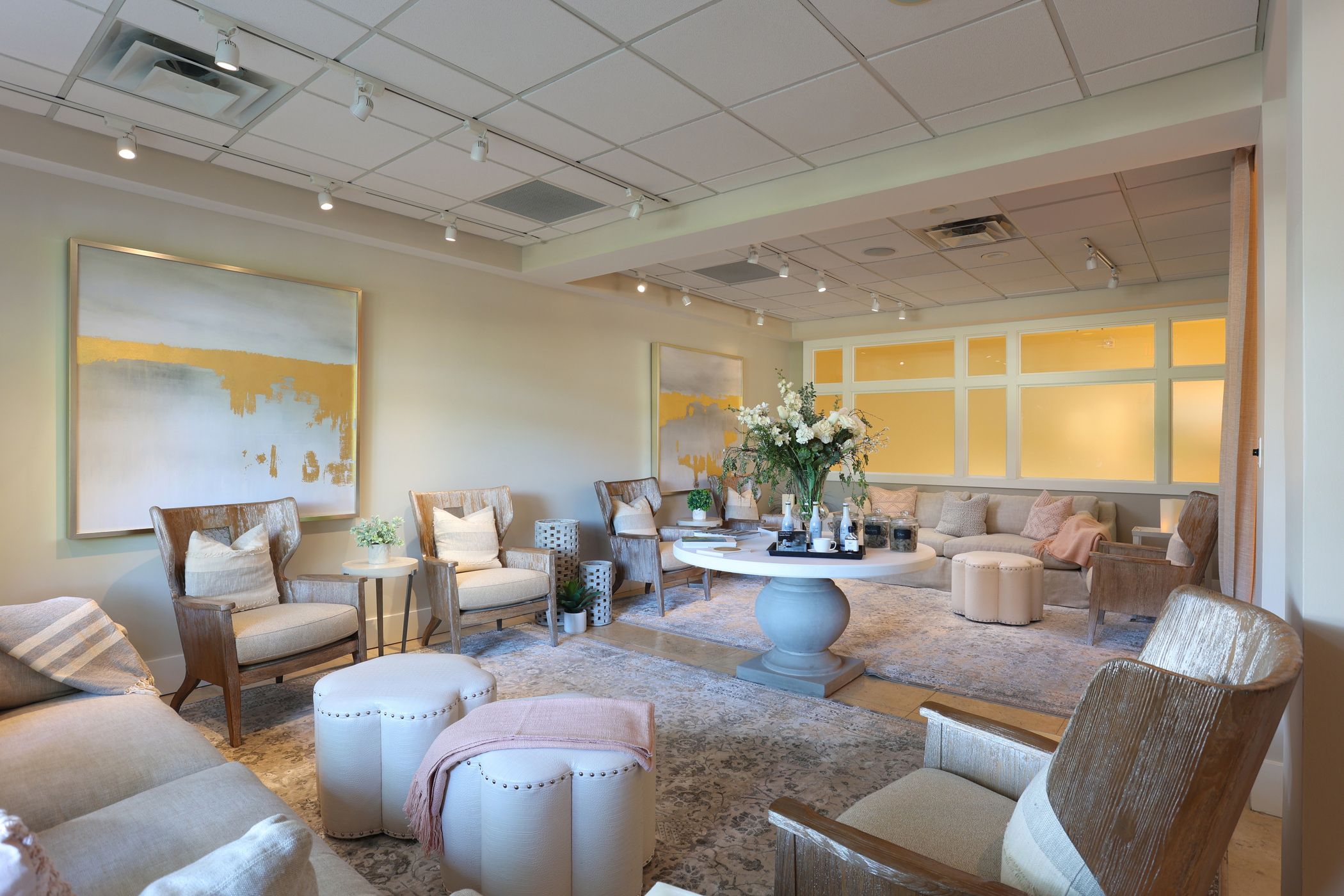 Wooden lounge chairs, couches, and floral arrangement inside peaceful beige and pink relaxation space, The Spa