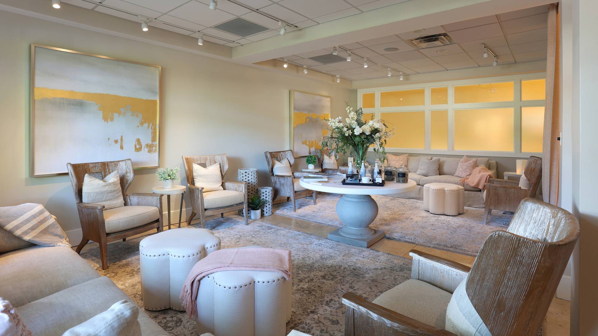 Wooden lounge chairs, couches, and floral arrangement inside peaceful beige and pink relaxation space, The Spa