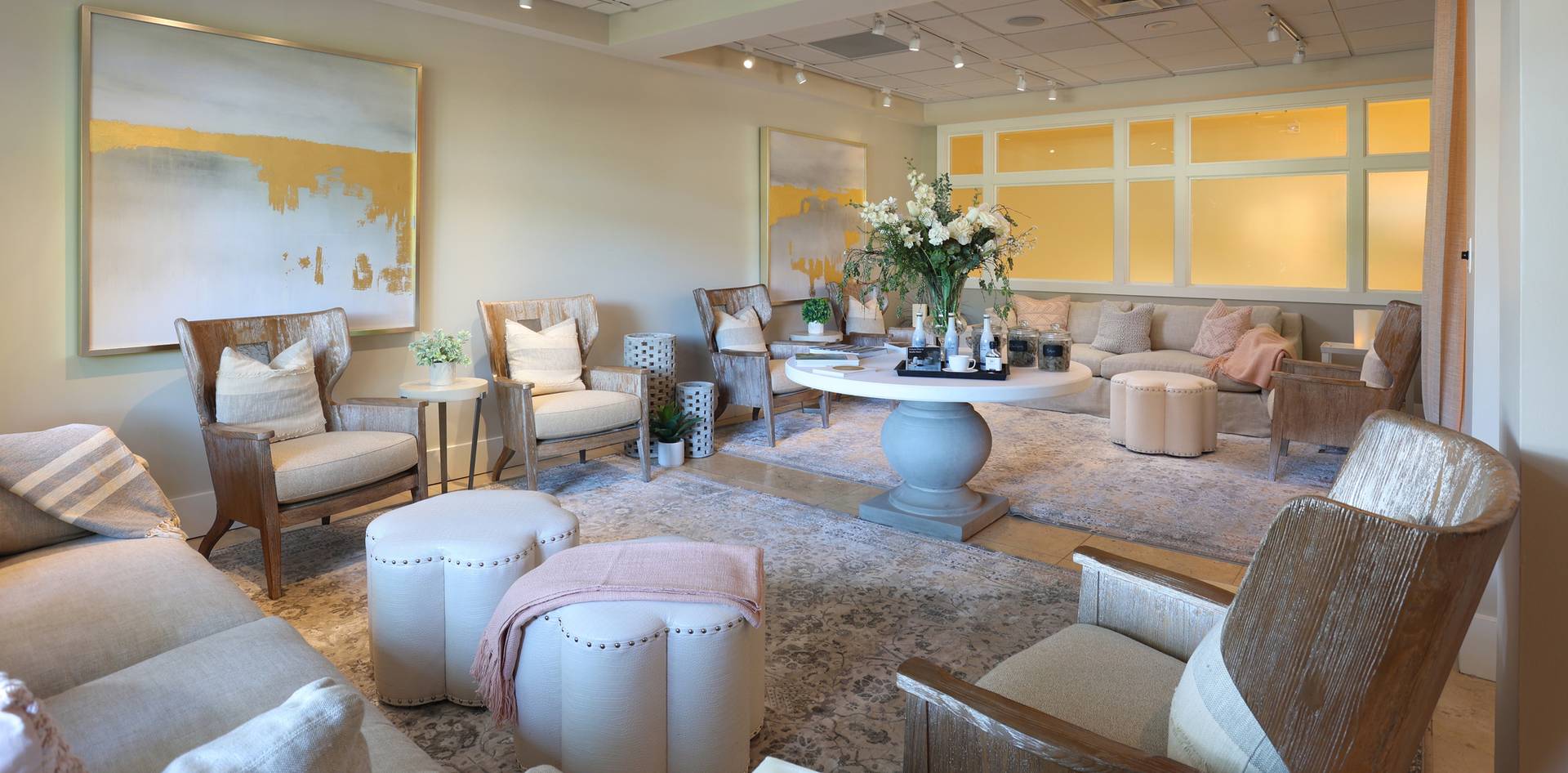 Wooden lounge chairs, couches, and floral arrangement inside peaceful beige and pink relaxation space, The Spa