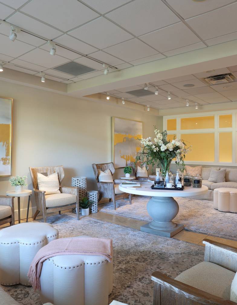 Wooden lounge chairs, couches, and floral arrangement inside peaceful beige and pink relaxation space, The Spa