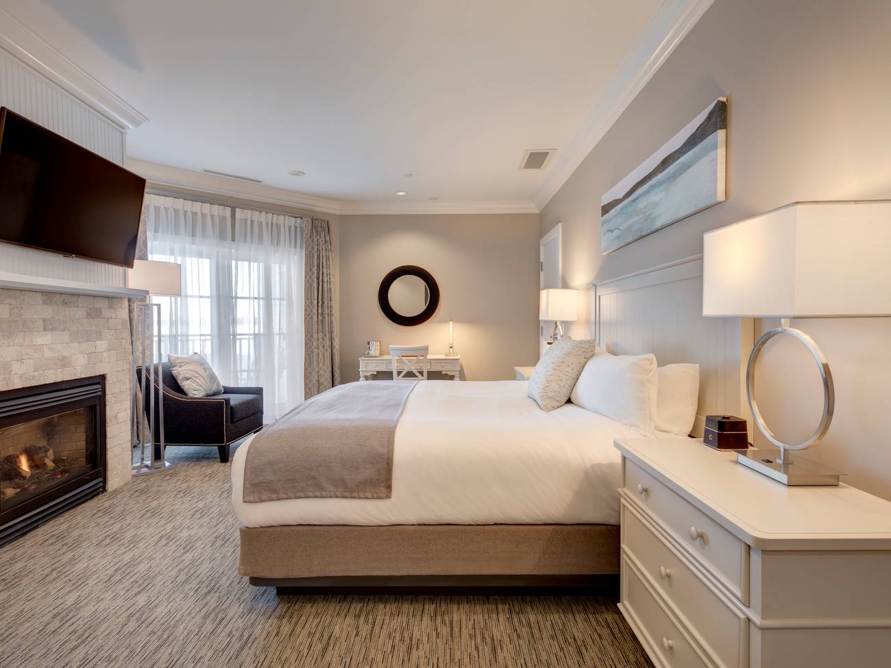 Side view of king bed, stone fireplace in front of decor in Tower King hotel room