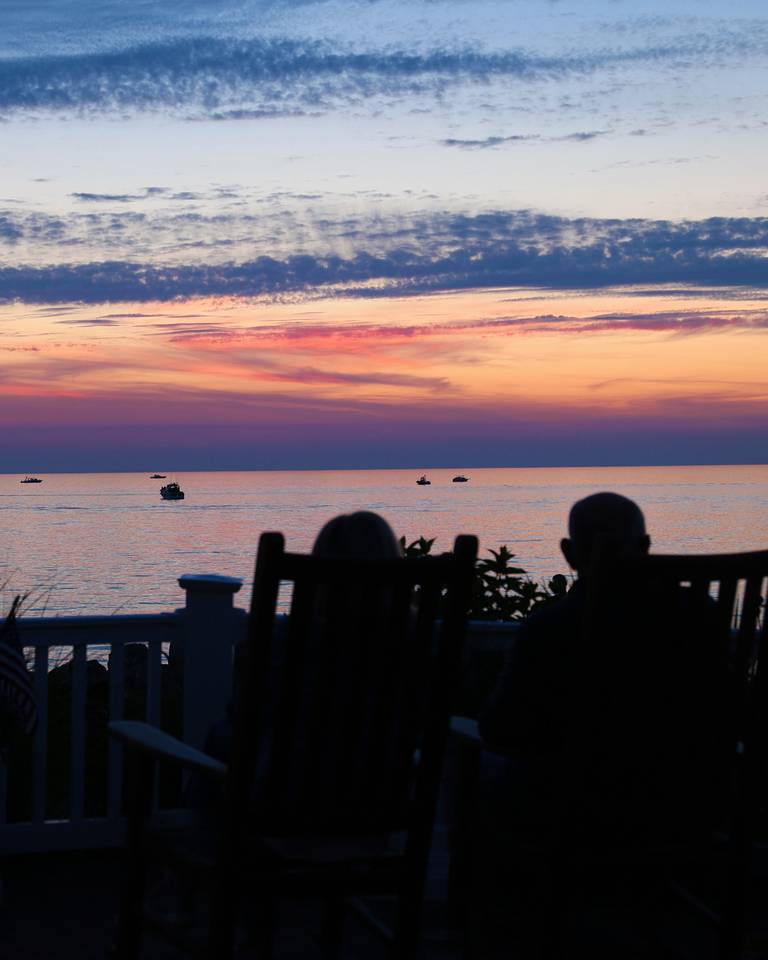 Shadow of couple in rockers overlooking boats on Lake Michigan at sunset