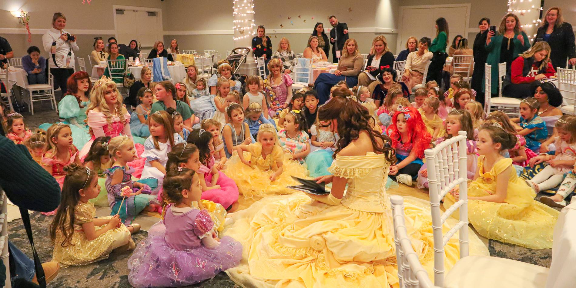Belle character reads to young Princess Gala guests