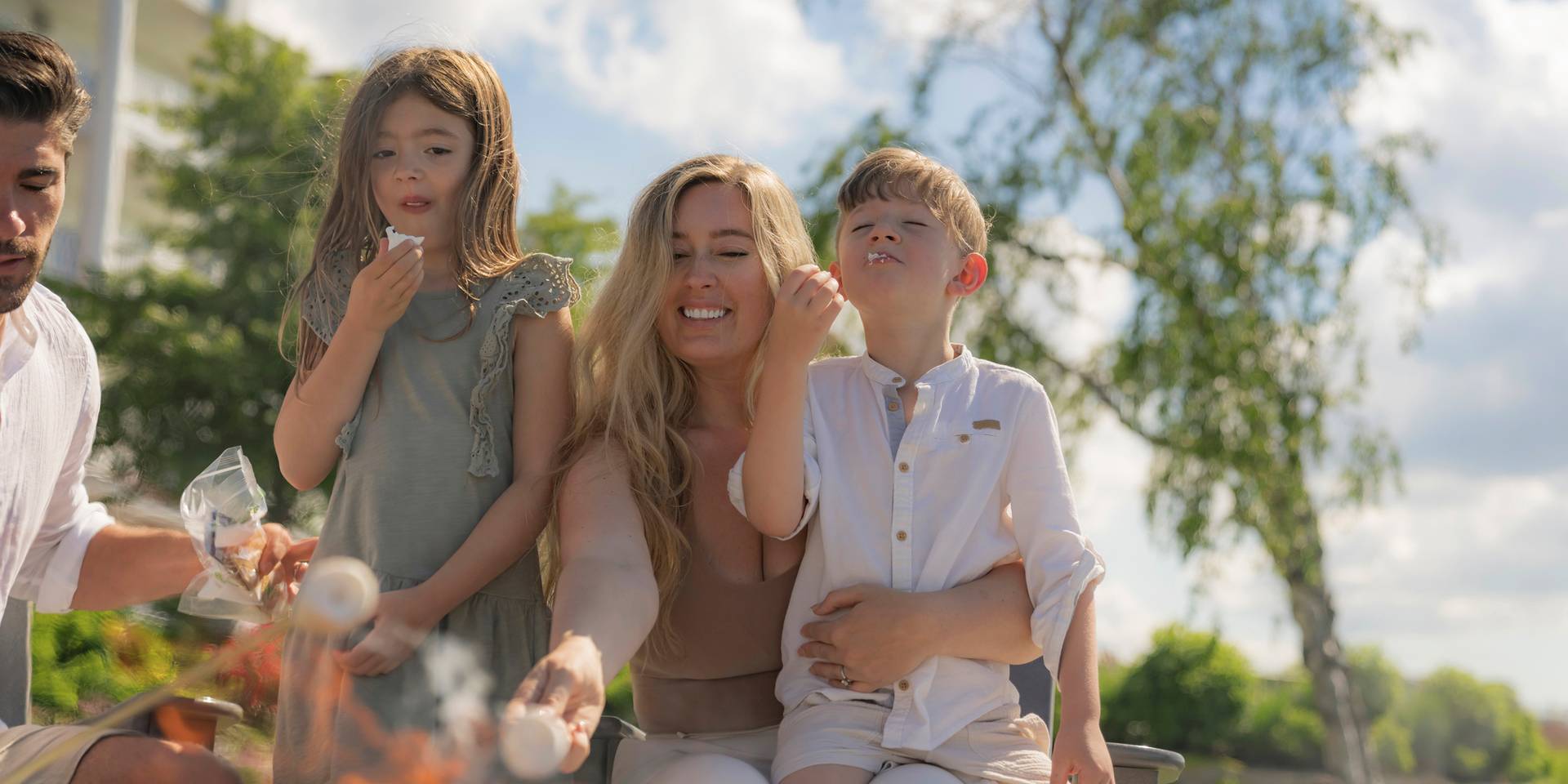 A family roasting marshmallows together on an outside bonfire