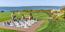 View of family playing giant chess on scenic lakefront game lawn alongside colorful flowers