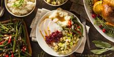 Top view of hearty Thanksgiving plate and table, with turkey, stuffing, potatoes, and more