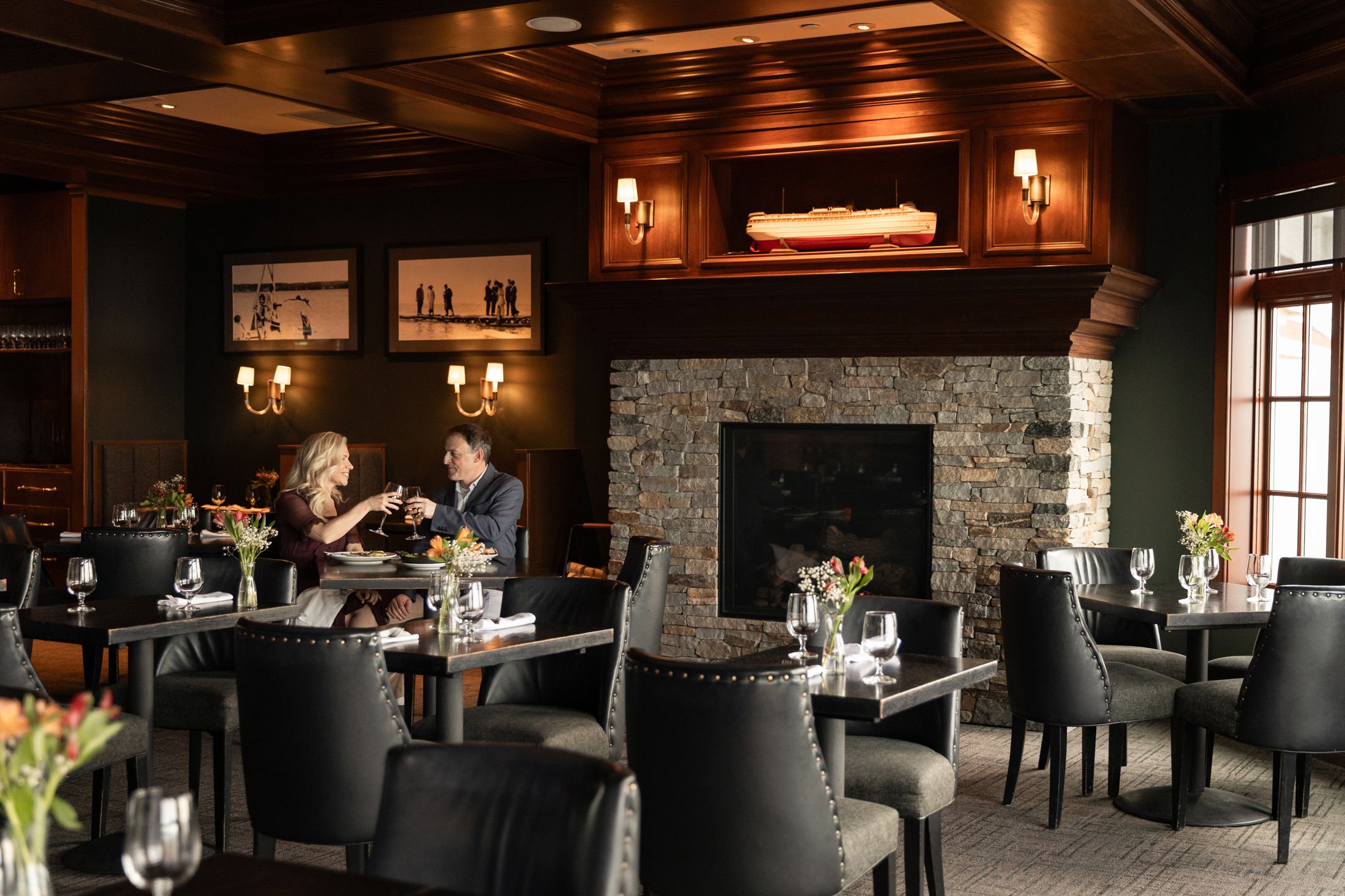Smiling couple toasts wine in romantic, dim dining room, Vintage Chophouse at Inn at Bay Harbor
