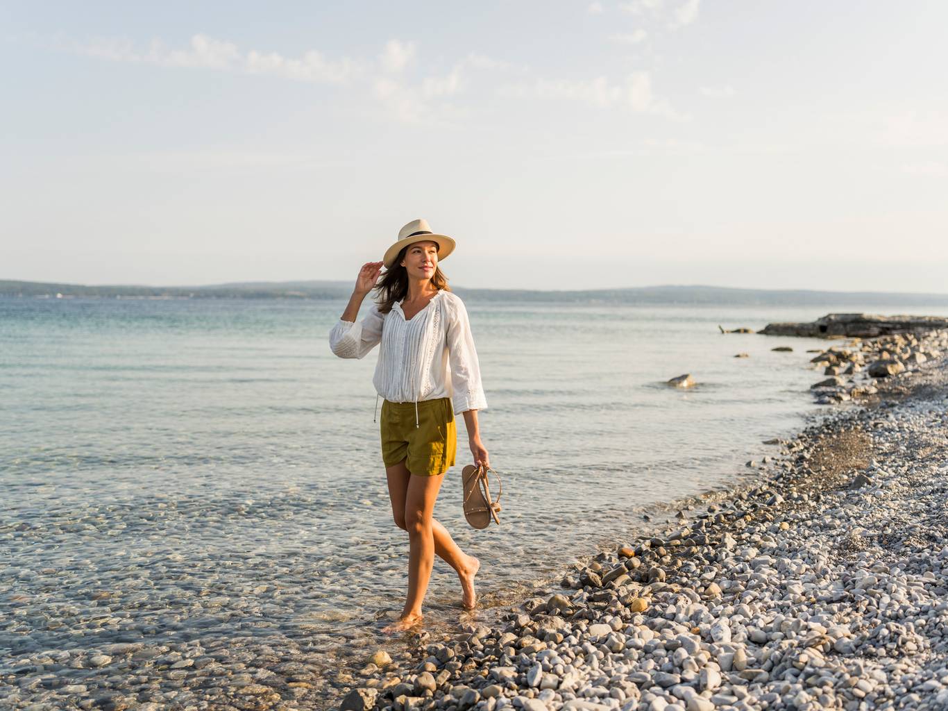 Young woman looks back from stony Lake Michigan beach walk