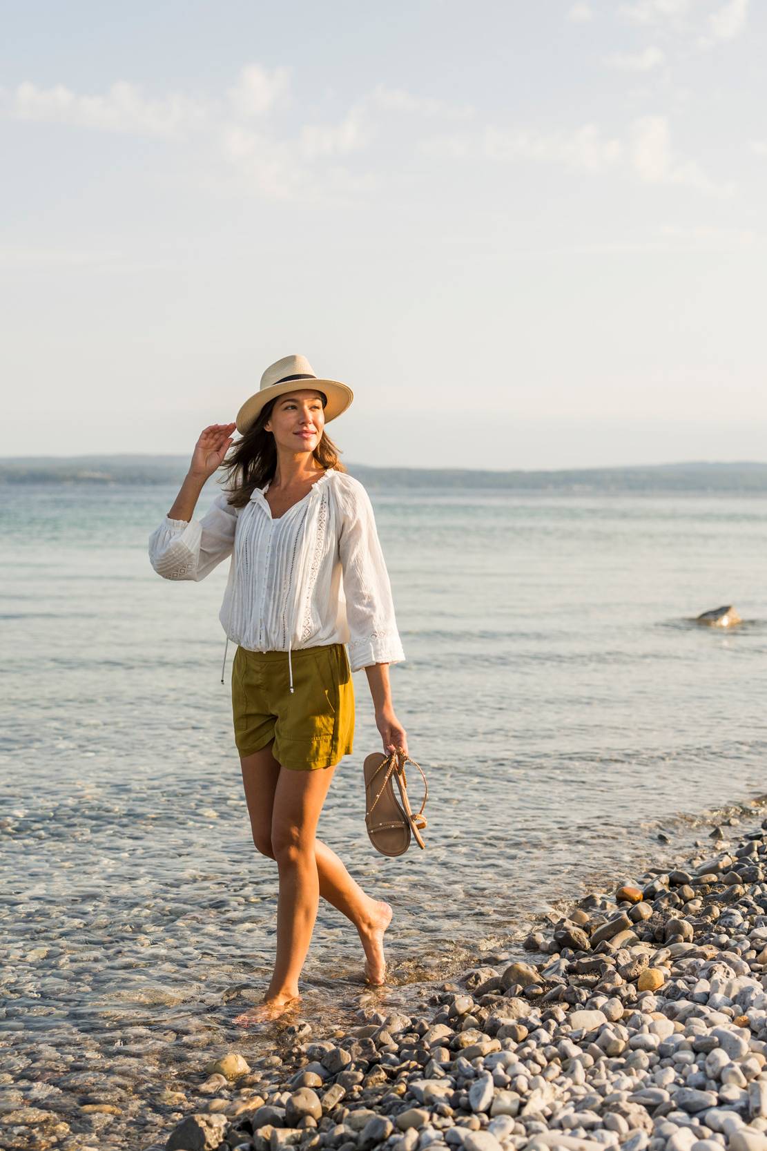 Young woman looks back from stony Lake Michigan beach walk