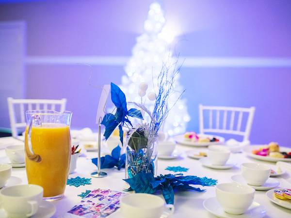 Breakfast and tea cups with blue sparkling table decor and white lit tree