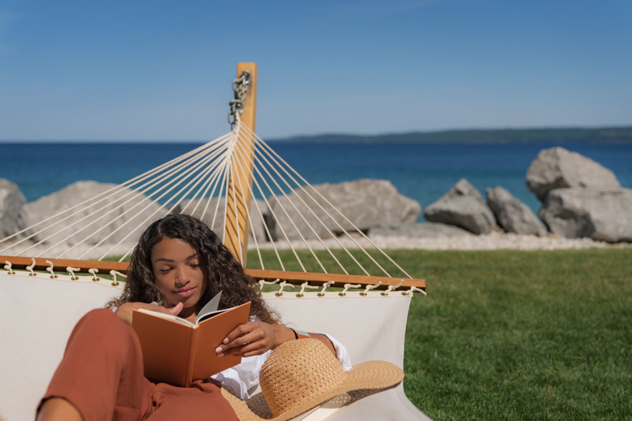 Young woman reading in hammock near rocky shore of Lake Michigan