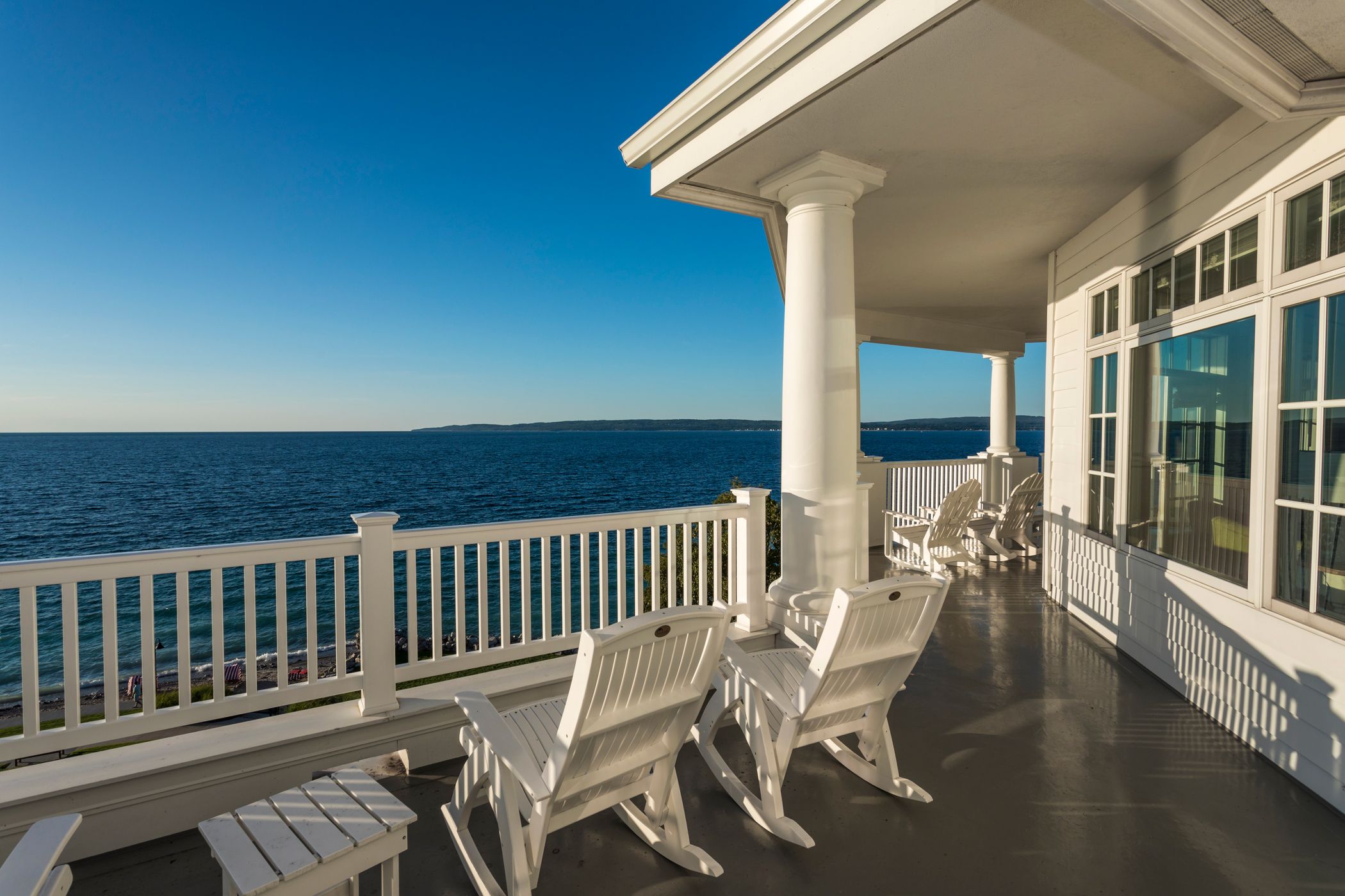 White rocking chairs on large balcony overlooking blue waters of Lake Michigan during golden hour