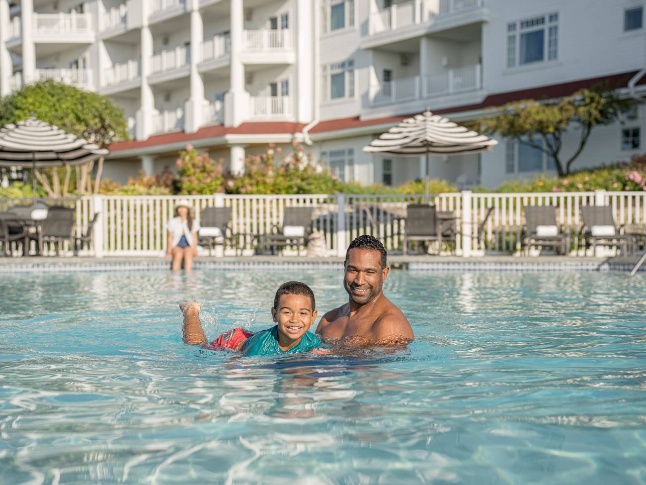 Smiling father and young son practice swimming, Inn at Bay Harbor outdoor pool