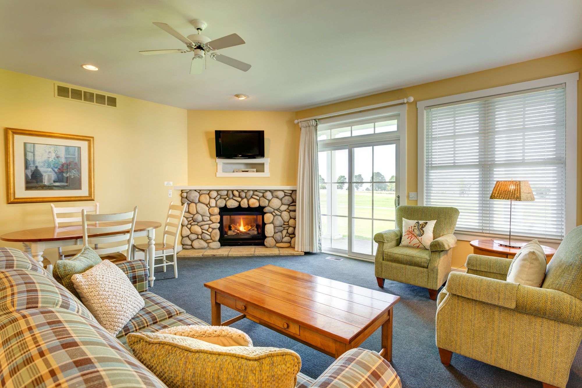 Wide view of living area with stone fireplace, couch and chairs, Crooked Tree Cottages