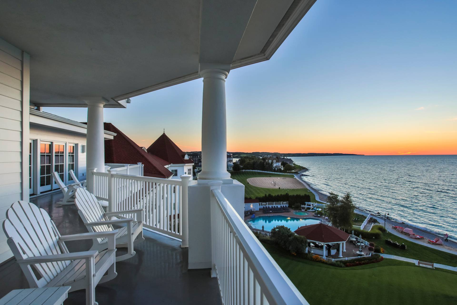 White adirondack chairs on upper balcony, overlooking grounds, pool, and Lake Michigan at Inn at Bay Harbor