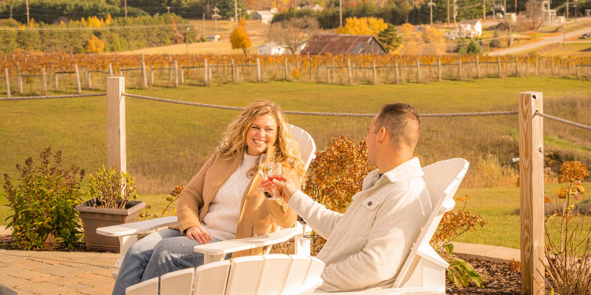 Smiling couple toasts with wine while sitting outdoors at autumn winery