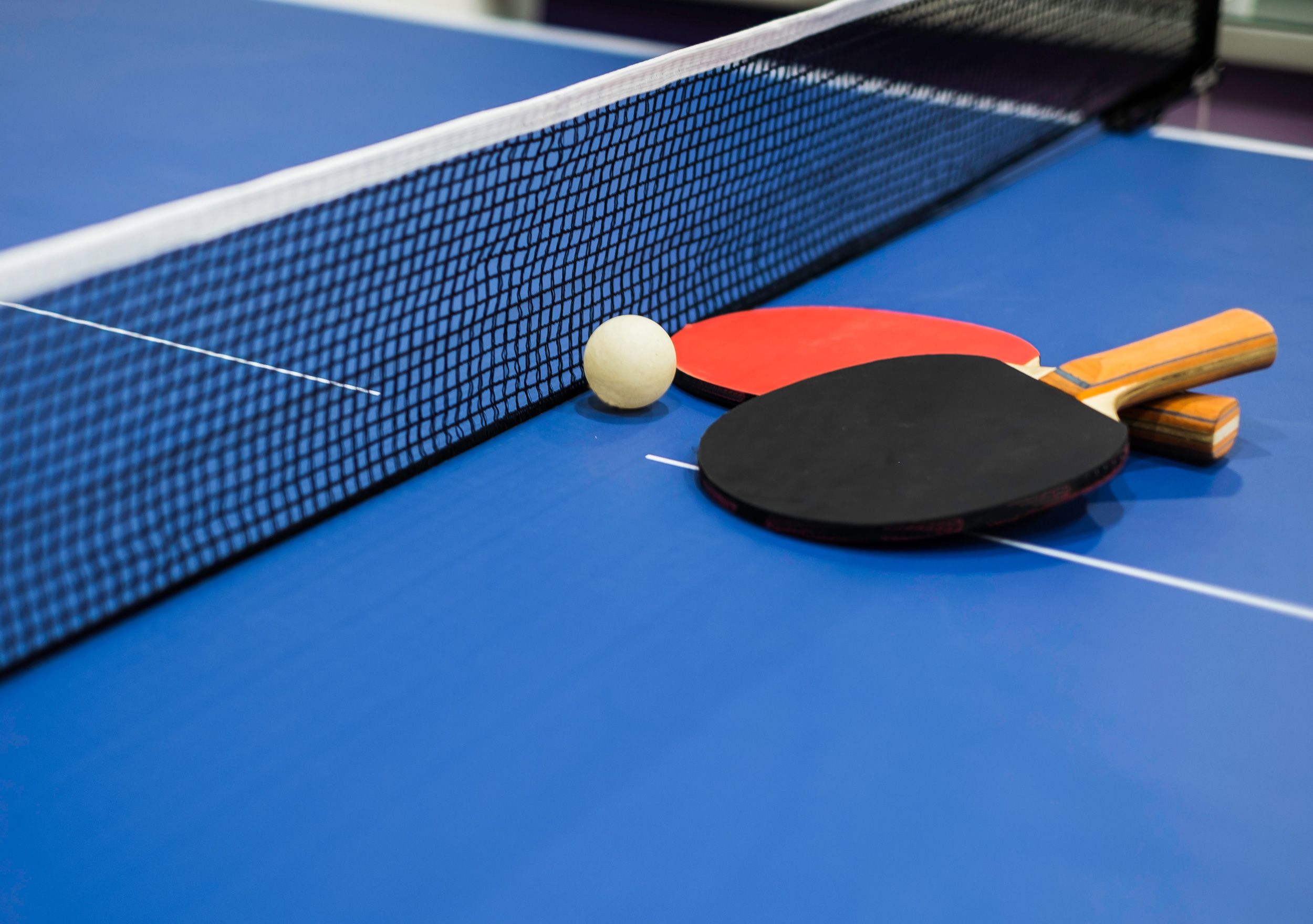 Black and red table tennis paddles resting on blue game table