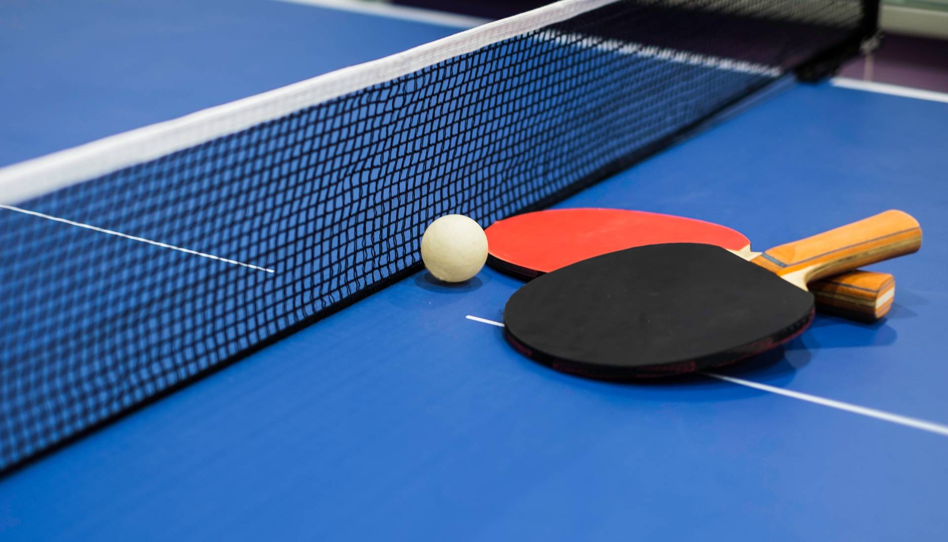 Black and red table tennis paddles resting on blue game table