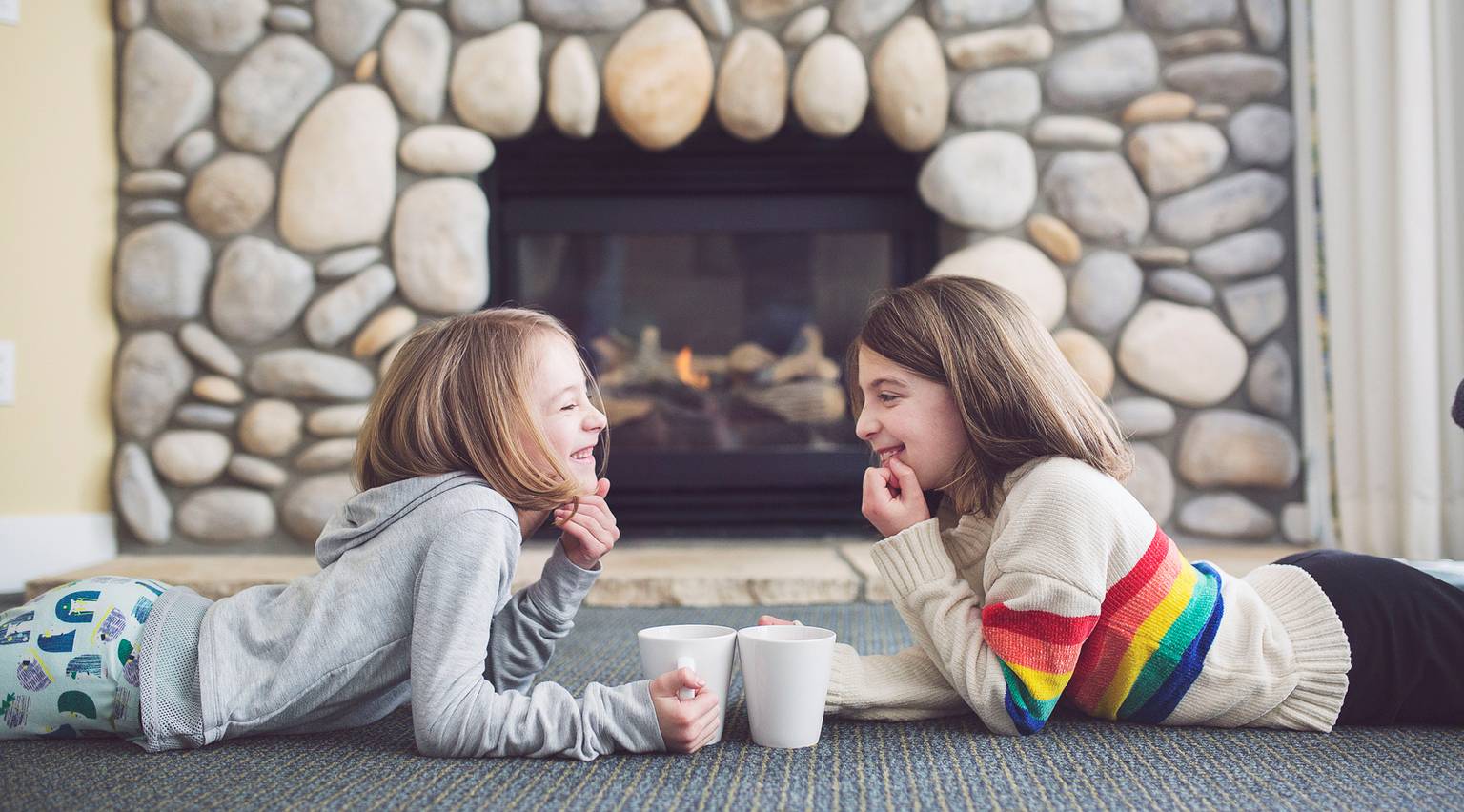 Girls laugh in front of stone fireplace