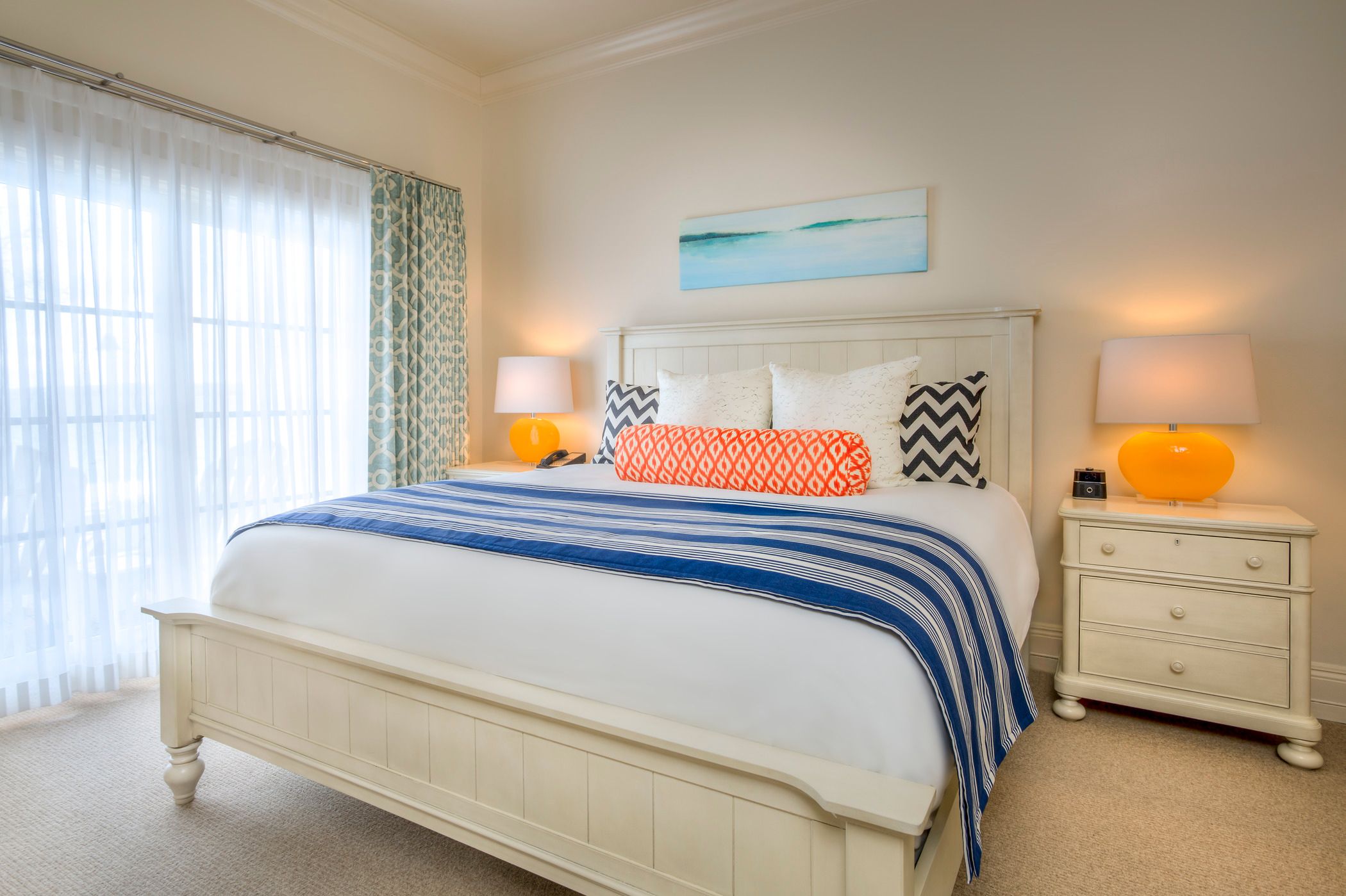 Colorful hotel bed, lamps near large window of Master Suite