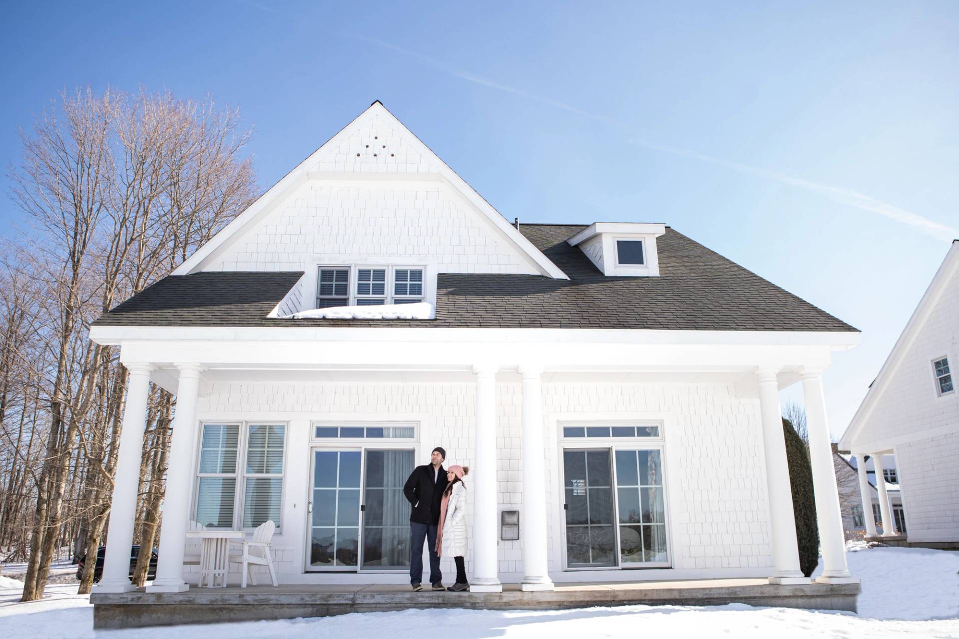 Couple in coats looks out to snowy view from Crooked Tree Cottages