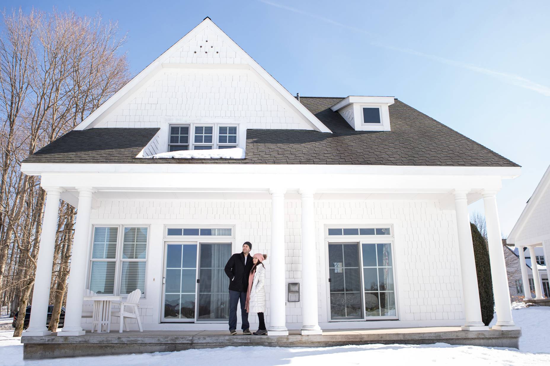 Couple in coats looks out to snowy view from Crooked Tree Cottages