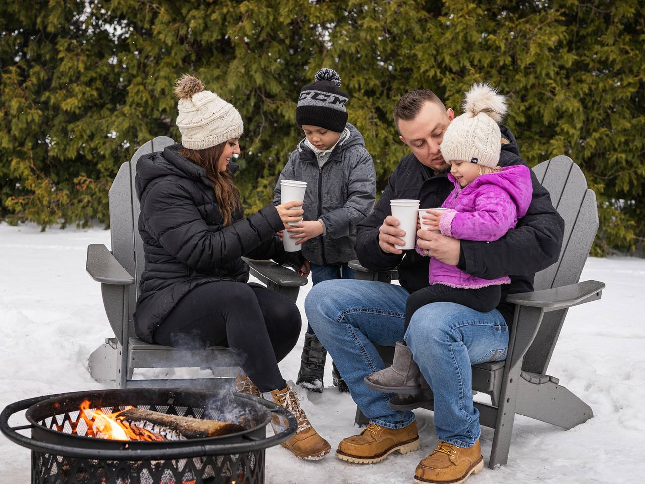 Family toasts with hot cocoa over winter bonfire