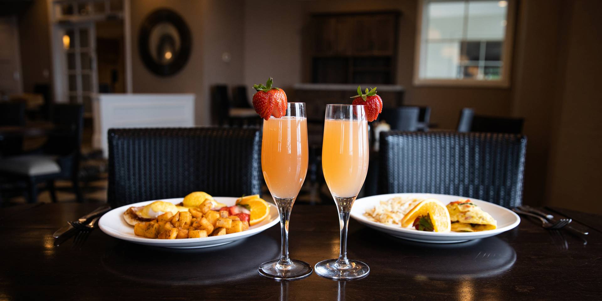 Two mimosas and breakfast plates atop dark restaurant table, The Sagamore Room of Inn at Bay Harbor