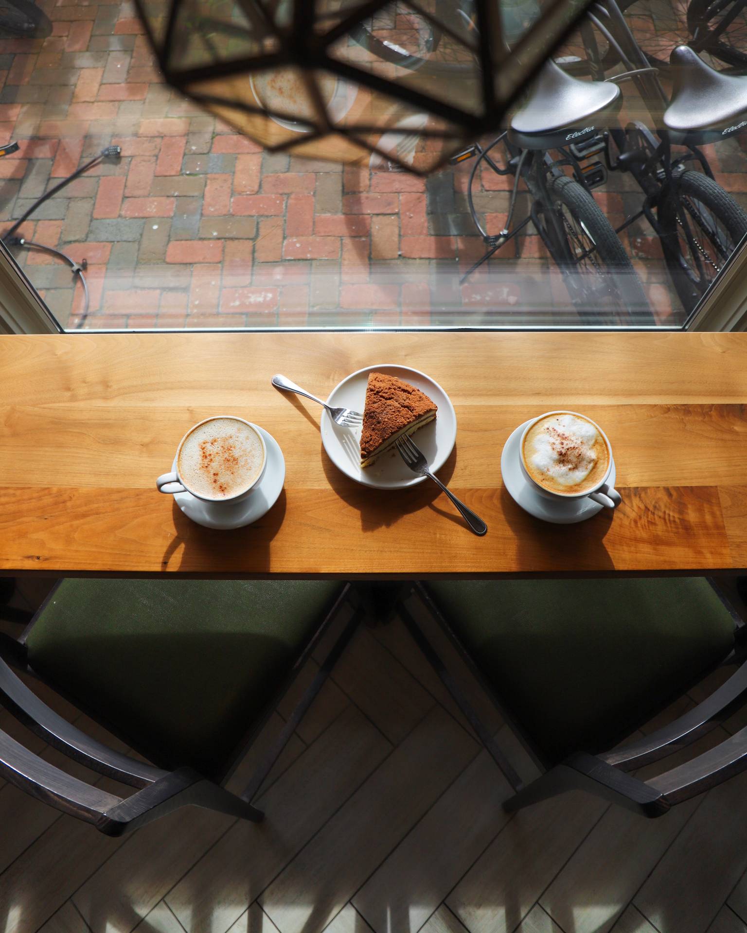 Downward view of foamy lattes and espresso with coffee cake, The Inn Cafe