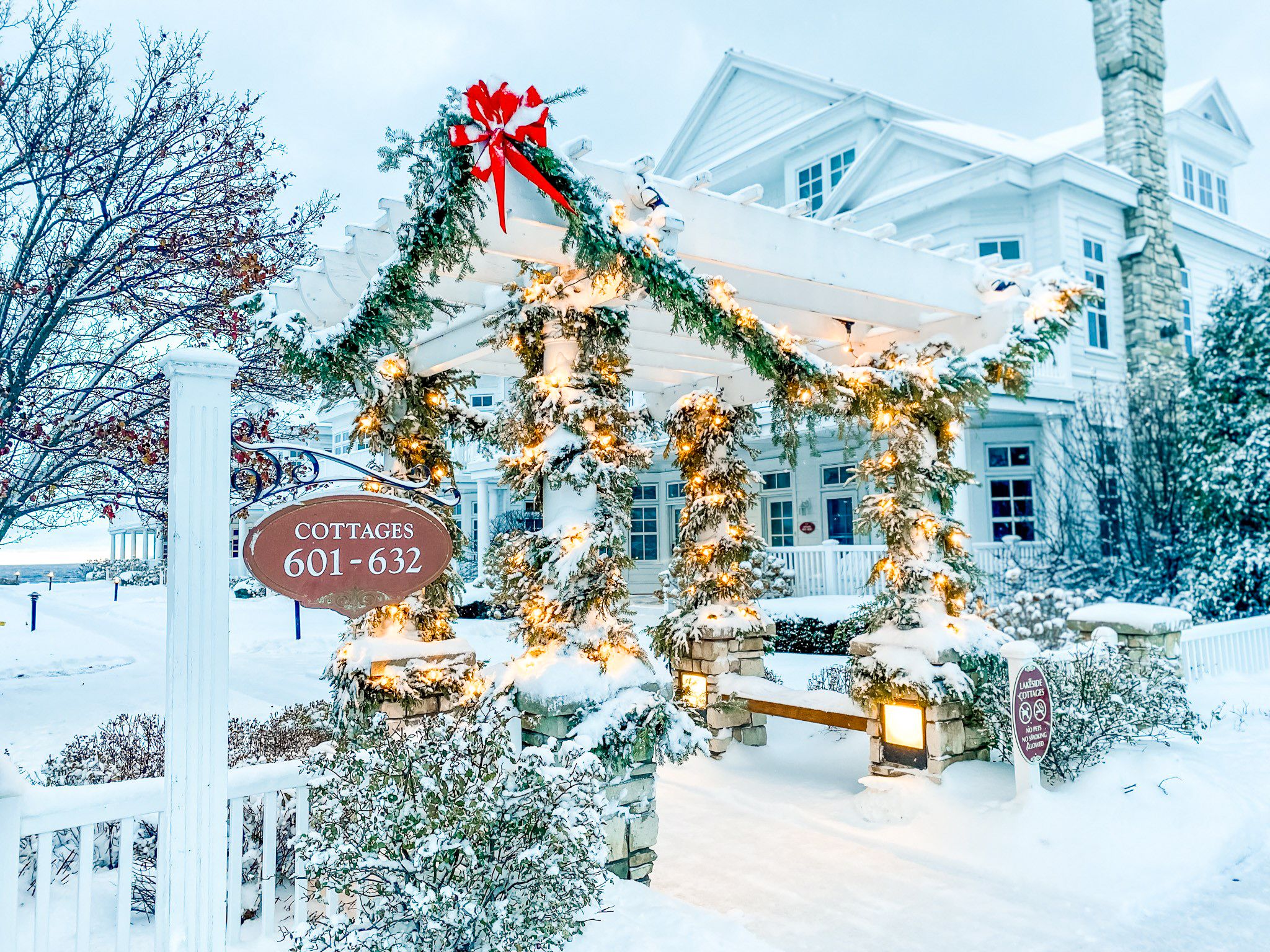 Snowy Lakeside Cottages gate with holiday lights