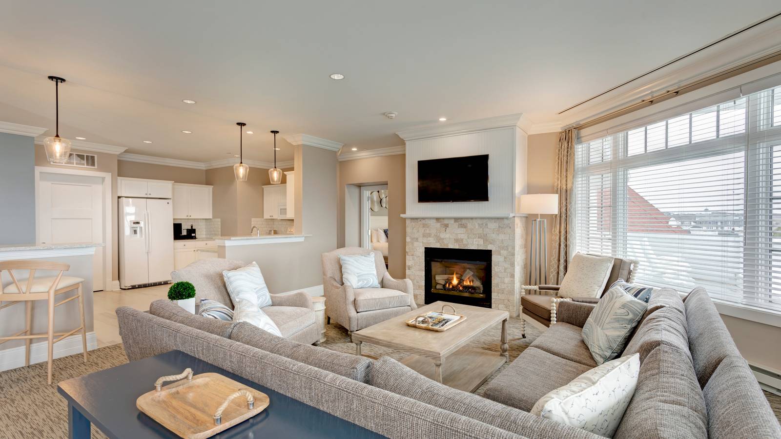 Inn at Bay Harbor Penthouse living area overview with sectional couch, chairs in front of fireplace, open from kitchen