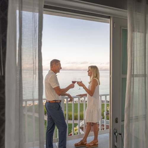 Smiling senior couple toasts with red wine on lake view balcony, Inn at Bay Harbor