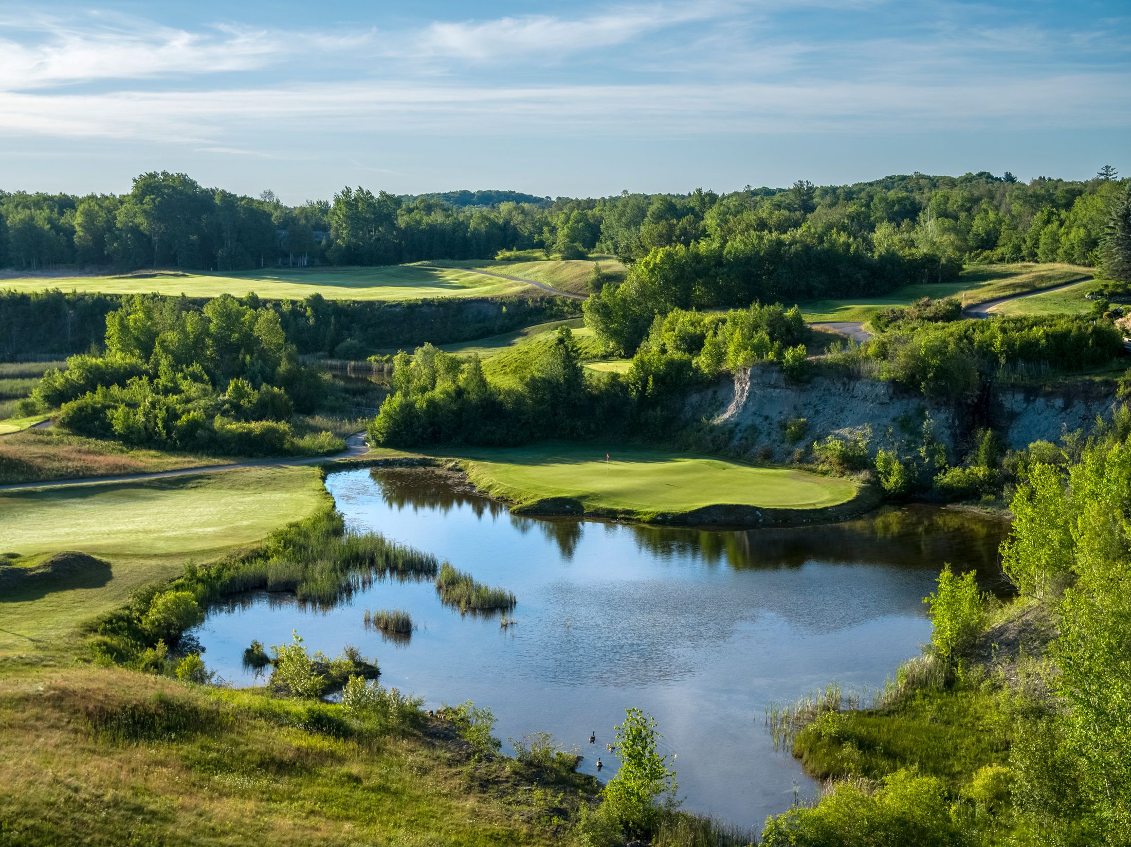 Scenic aerial view of rugged golf course at Bay Harbor Golf Club, with pond, lush fairways, limestone cliffs