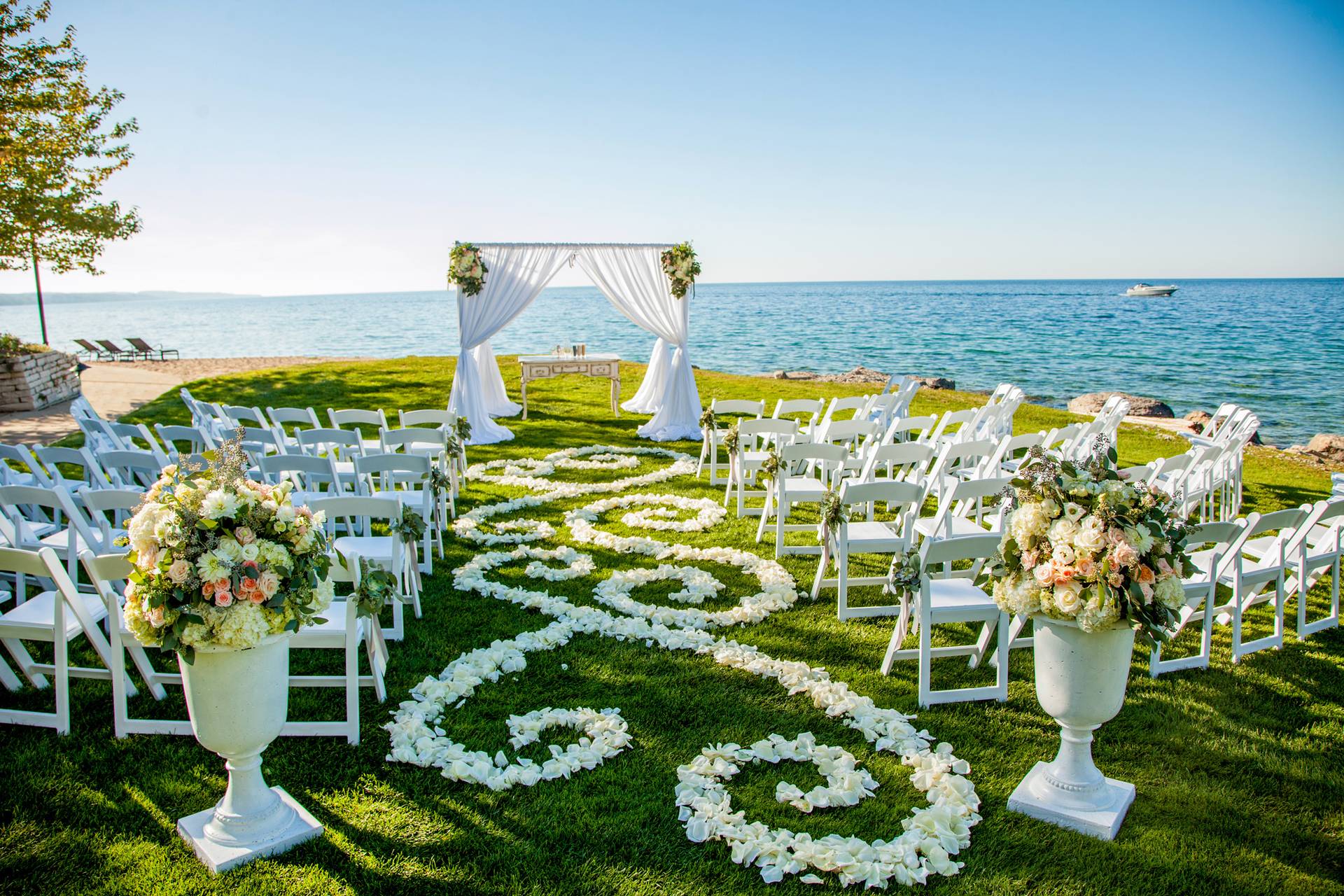 Elegant wedding ceremony setup with white florals and swirling petals on the Lake Lawn at Inn at Bay Harbor, overlooking Lake Michigan.