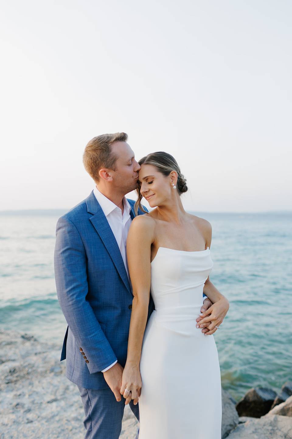 Newlywed couple smiles with water background