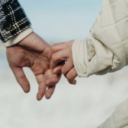 Couple's fingers, hands holding during romantic outdoor walk near lake