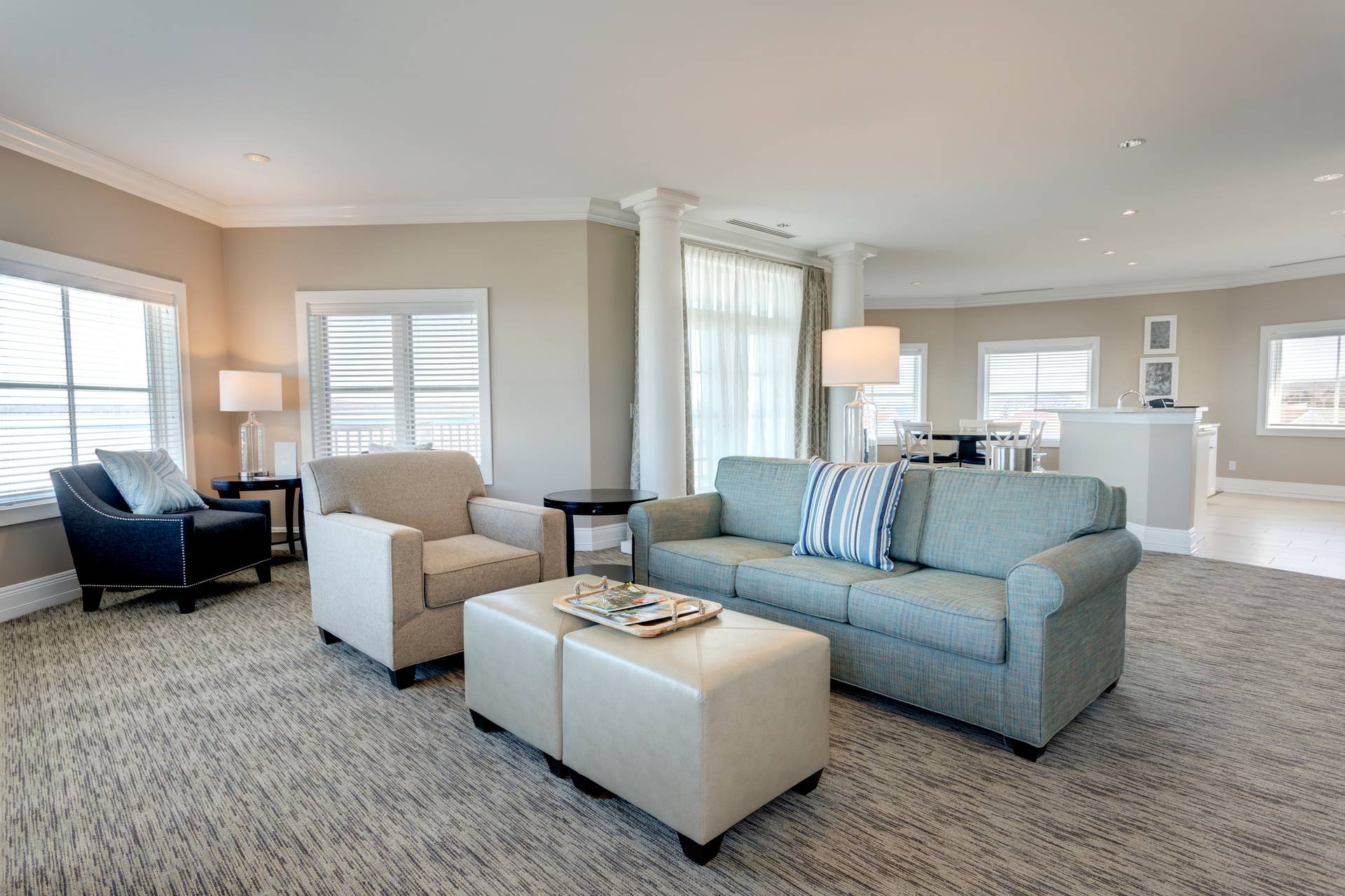 Open hotel room living area with large windows in front of kitchen and dining area