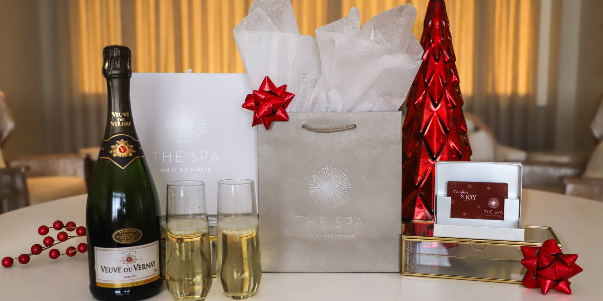 Champagne flutes, shopping bags, and red holiday bows at The Spa at Inn at Bay Harbor