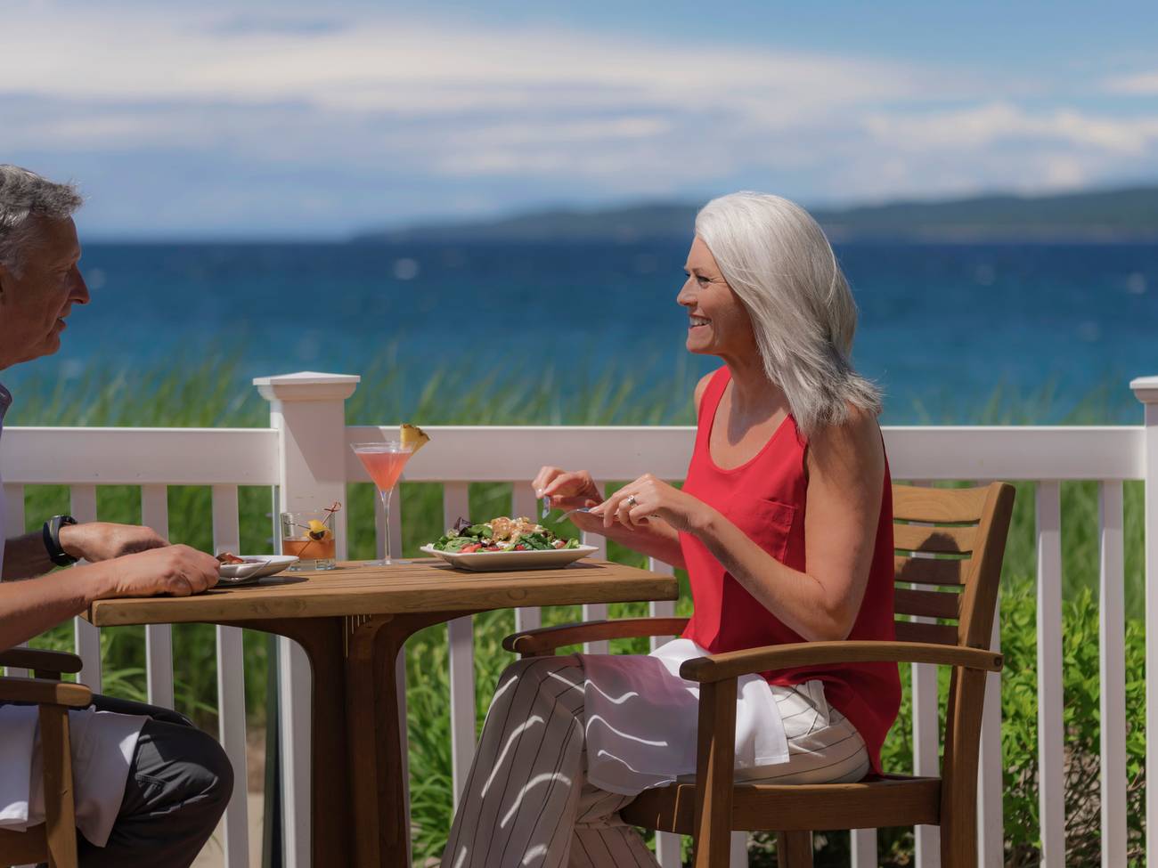 Senior couple eats lunch with cocktails on waterfront outdoor patio, Vintage at Inn at Bay Harbor