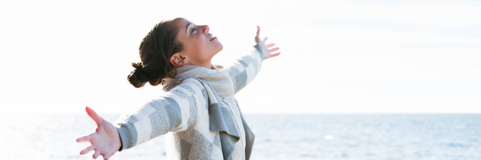Woman with open arms near blue water