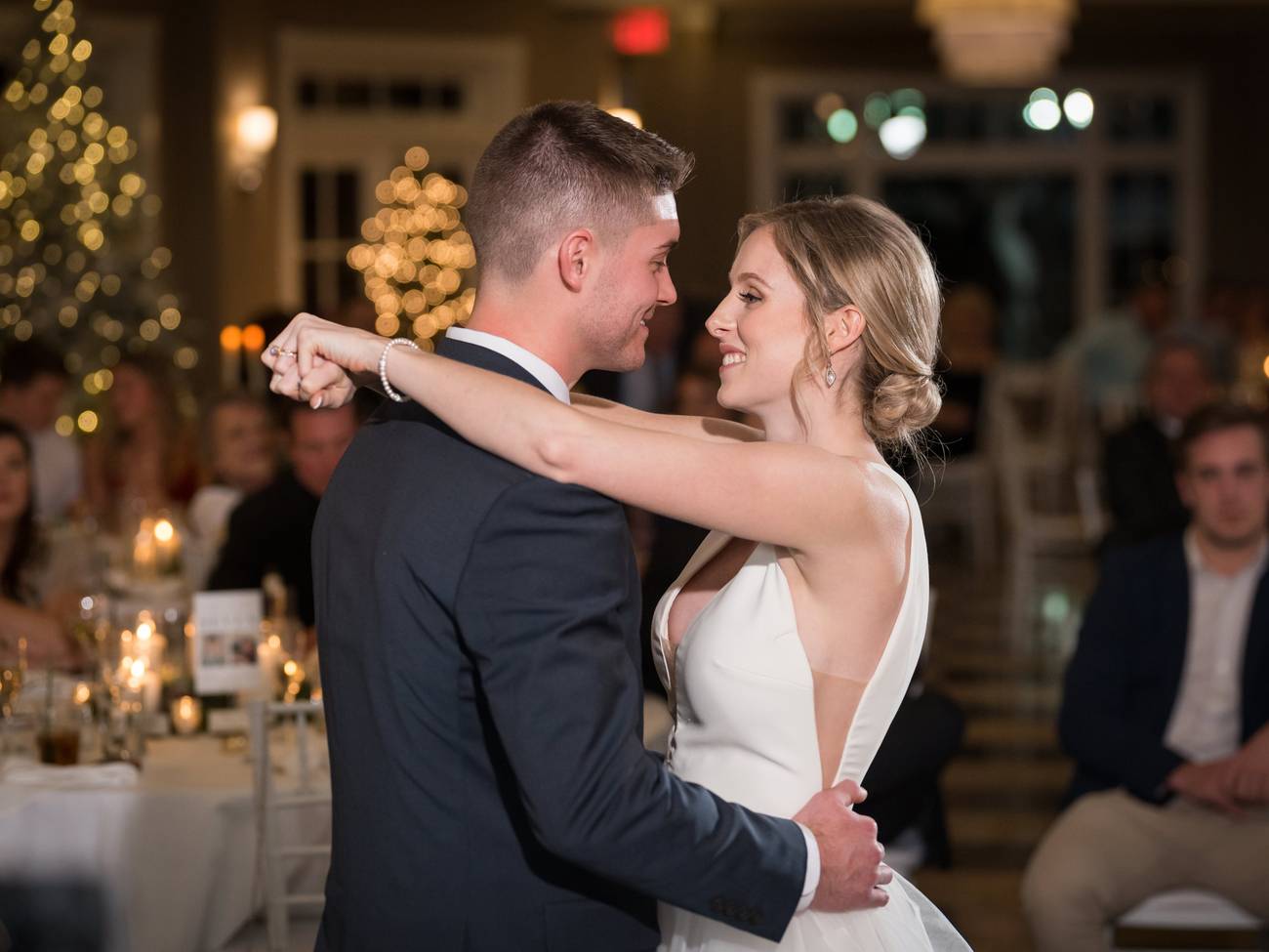 Newlyweds dance in front of guests, lit tree decor