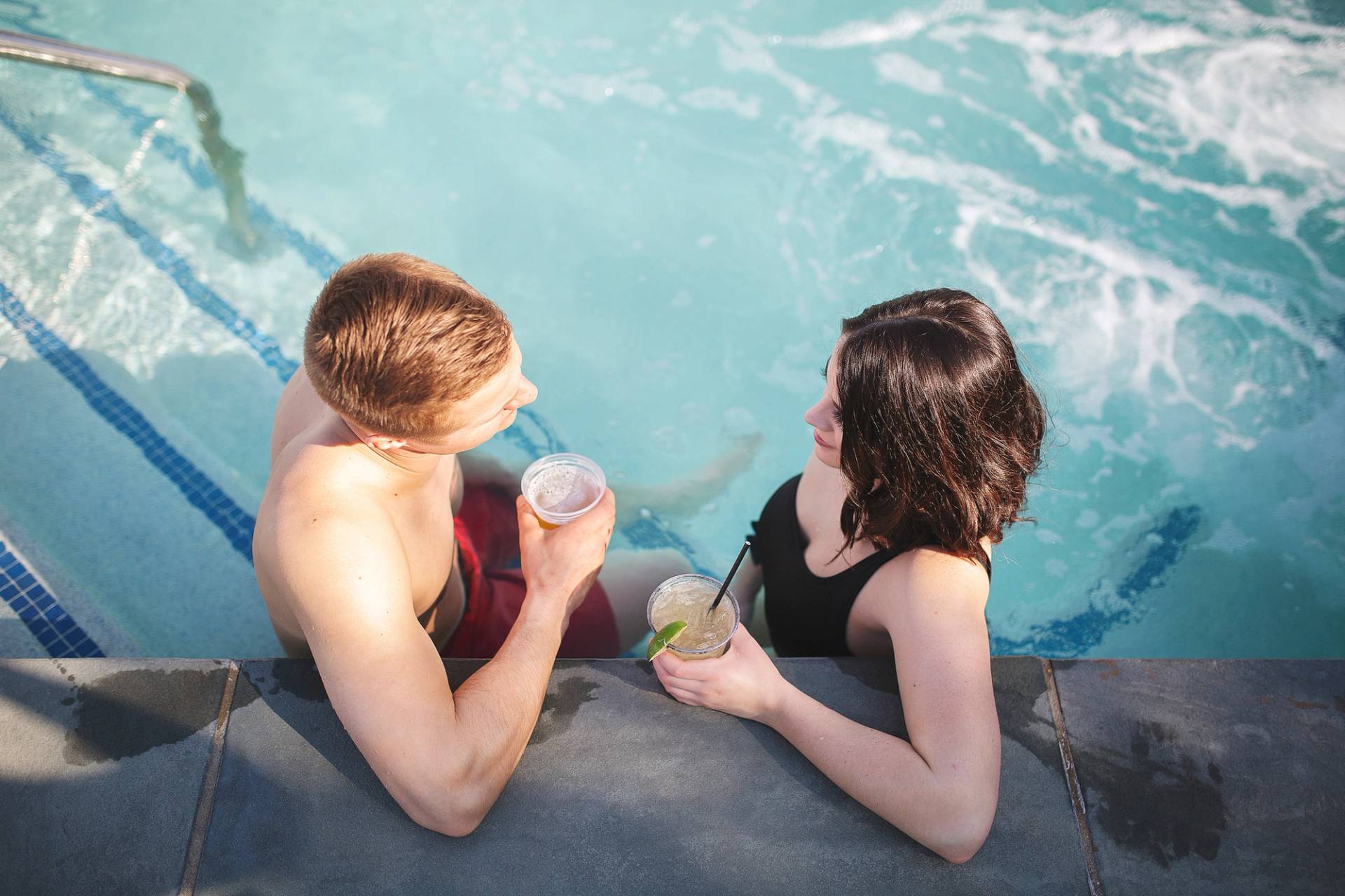A young couple enjoys drinks in a hot tub