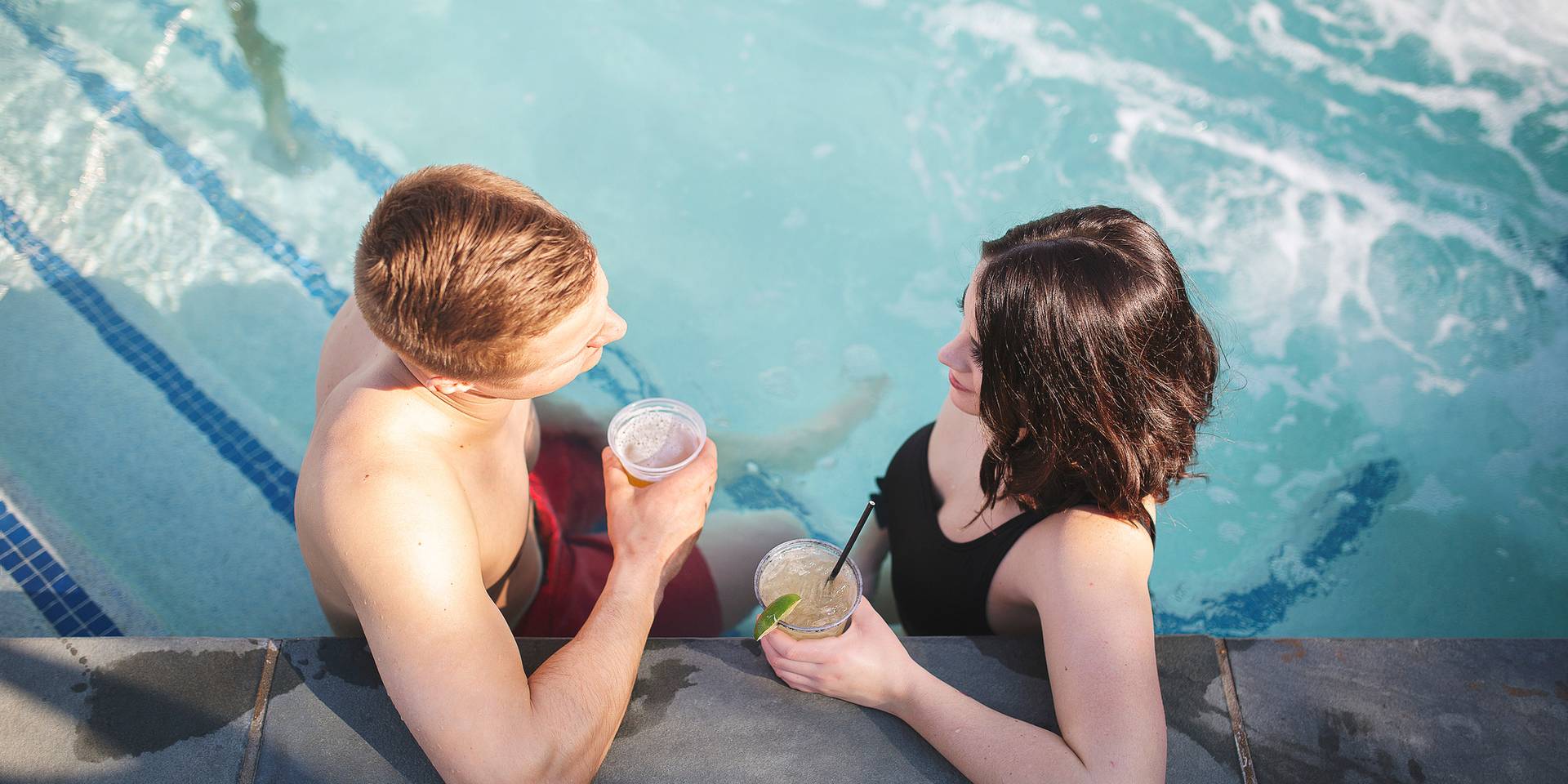 A young couple enjoys drinks in a hot tub