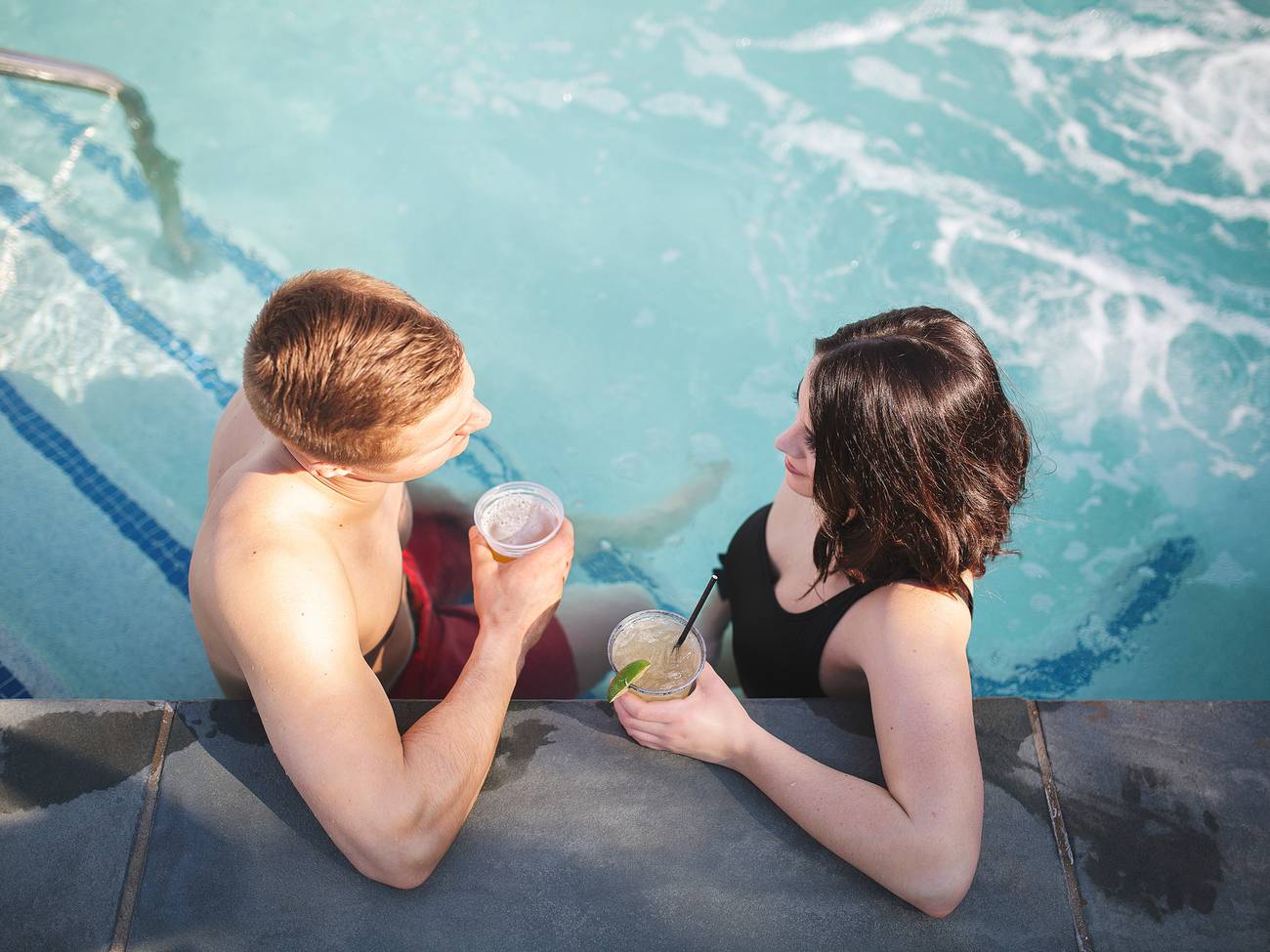 A young couple enjoys drinks in a hot tub