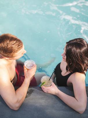 A young couple enjoys drinks in a hot tub